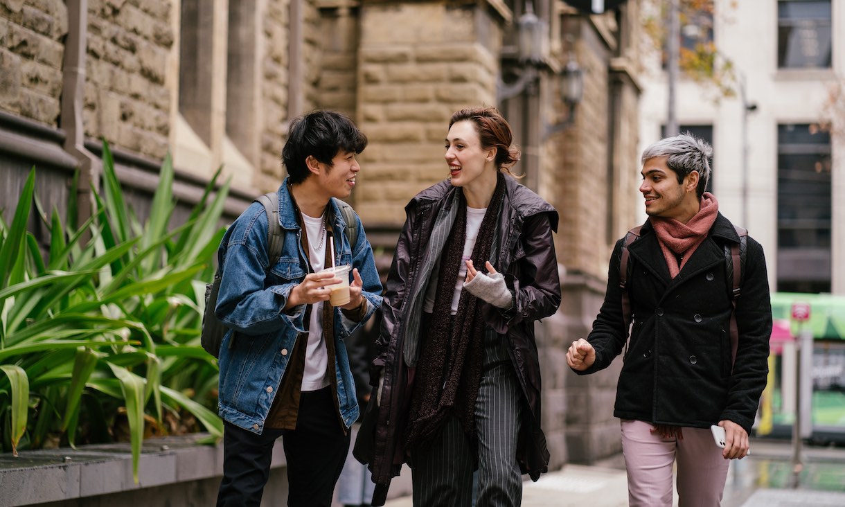 three students chatting while walking through RMIT city campus